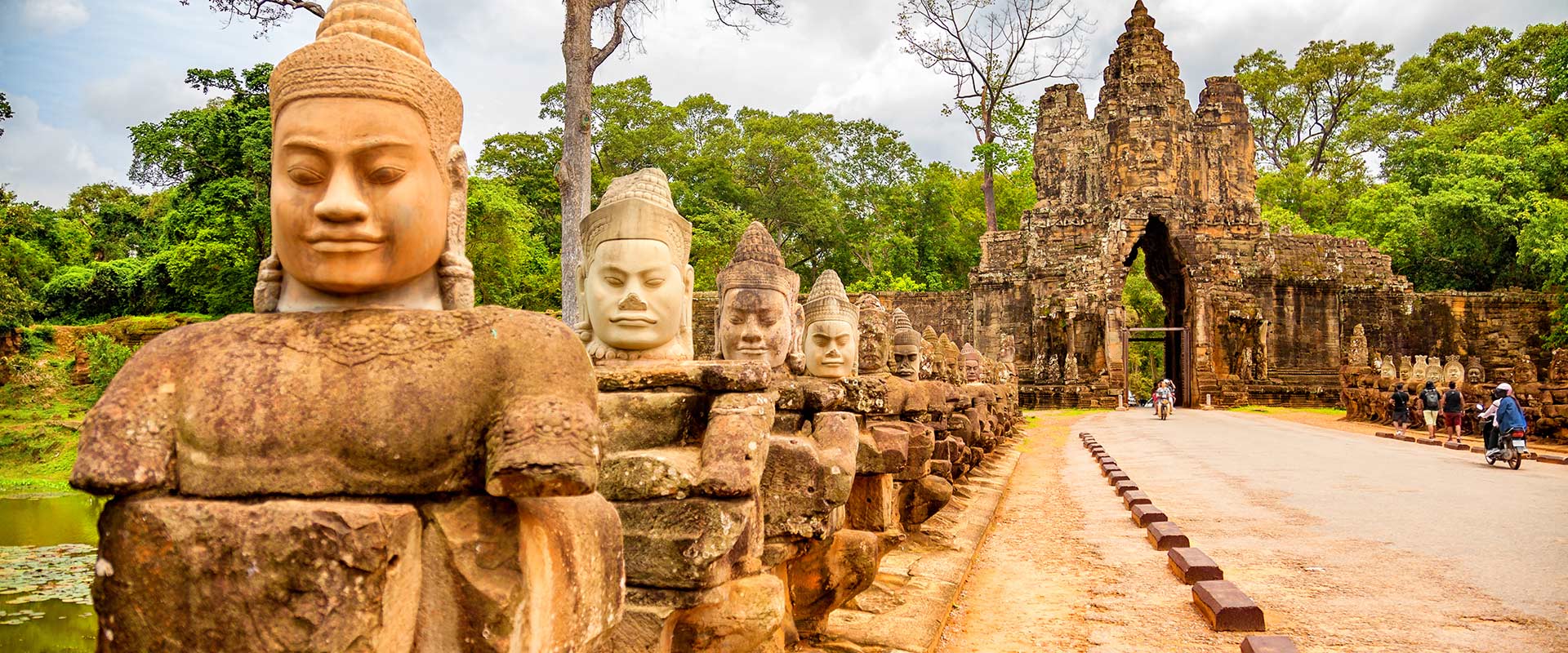 Row of carved men statues at the main gates to a stone temple, Cambodia