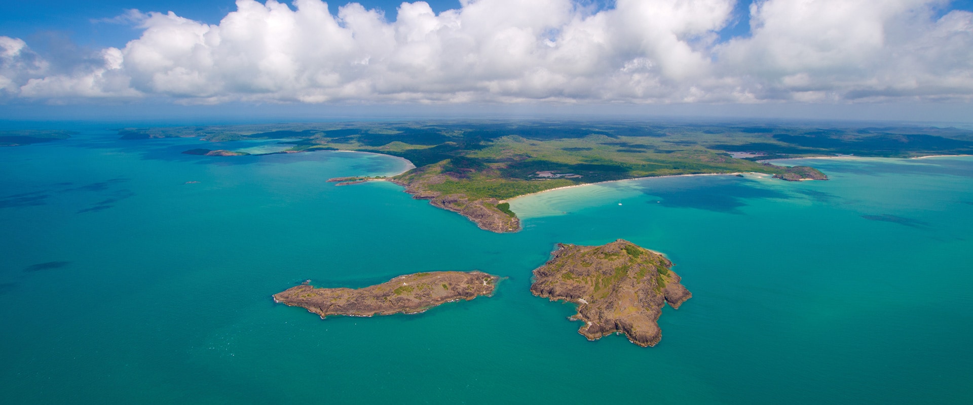 Aerial view of crystal clear blue waters with land in the distance, QLD