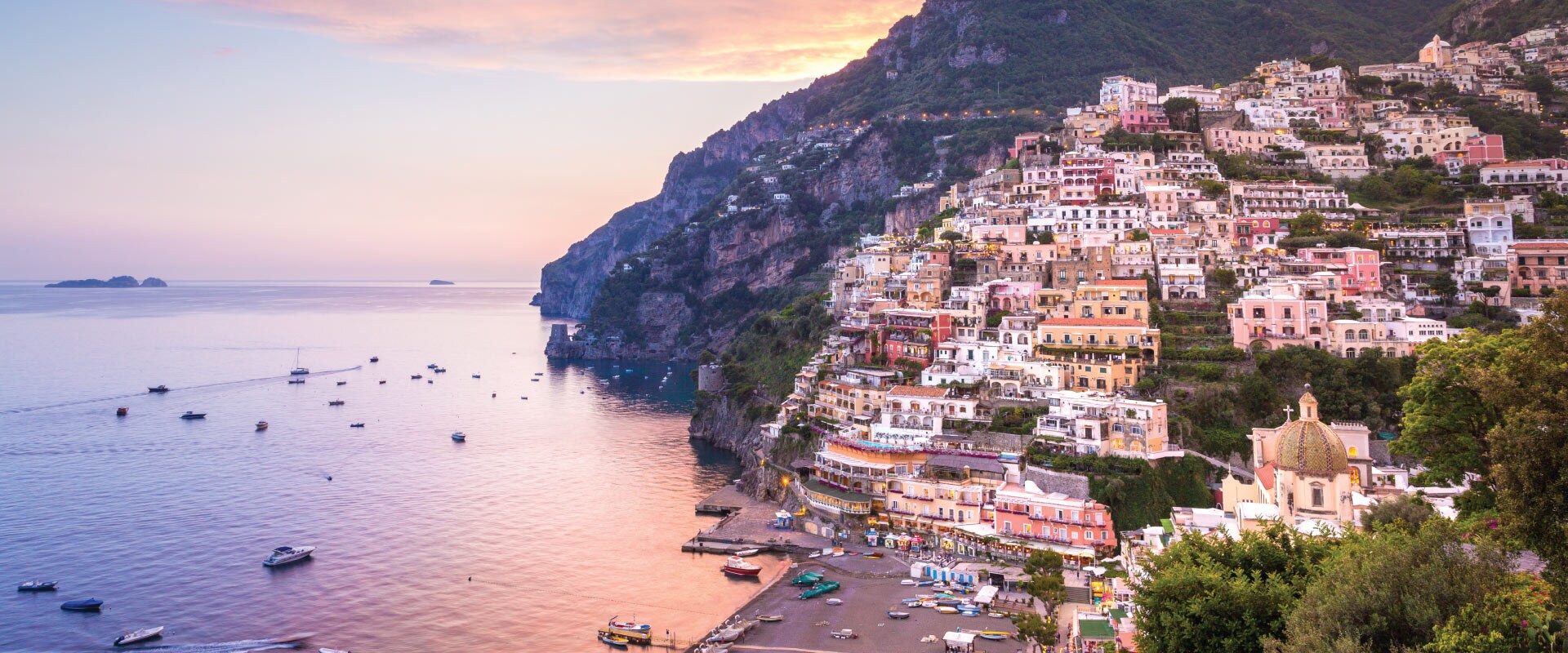 View of seaside town climbing the hill which looks out towards the ocean at sunset, Italy