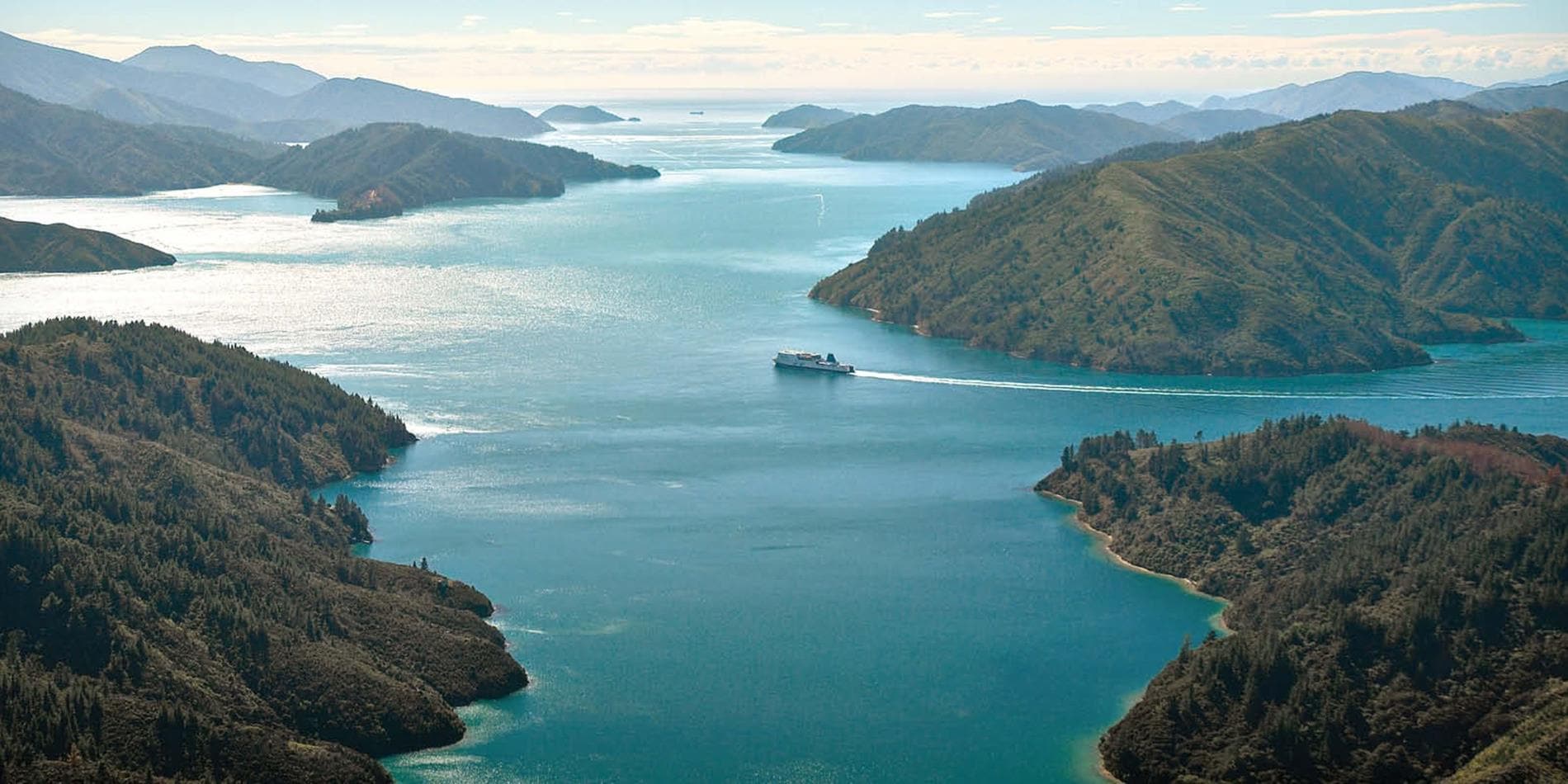 A distant view of the Interislander Ferry cruising past land formations