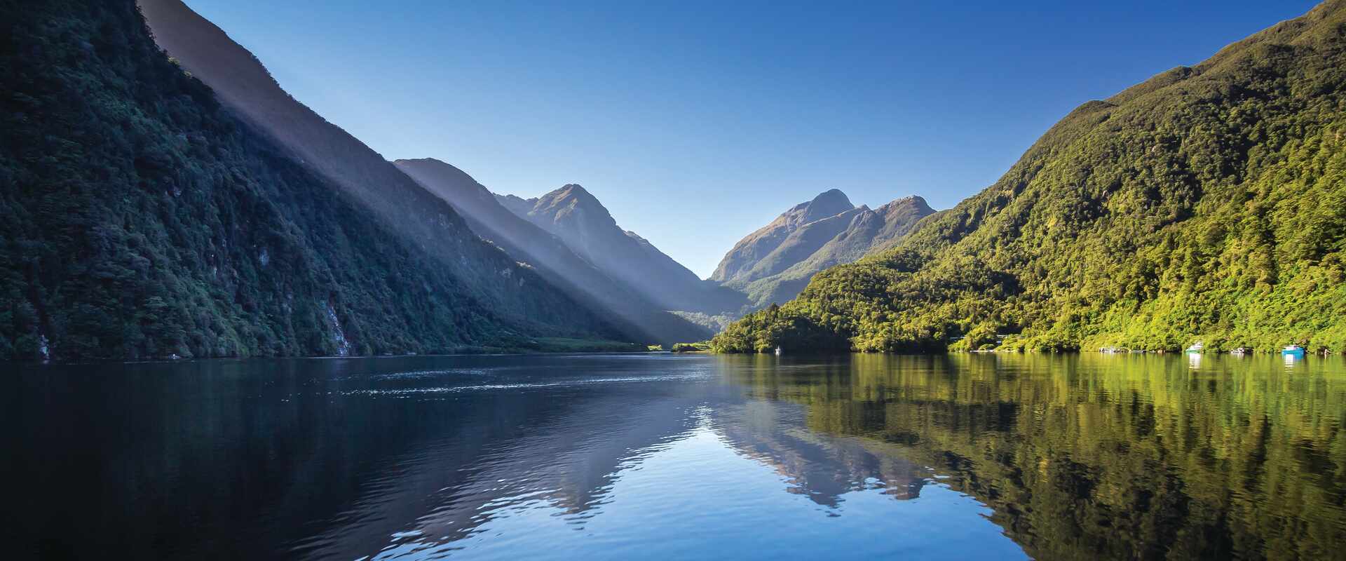 Still waters of Doubtful Sound where the green mountains meet the waters edge