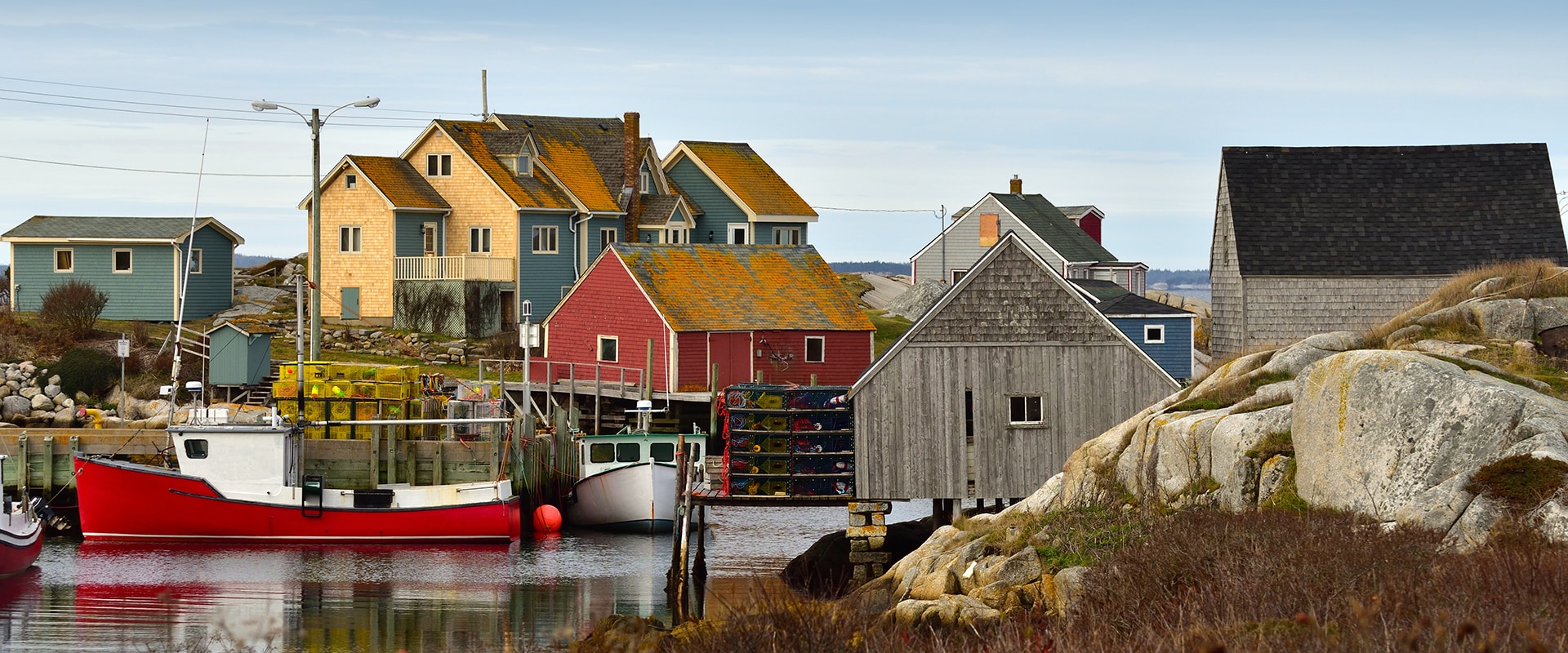 Colorful wooden houses built along the harbor with a red and white boat tied up at pier