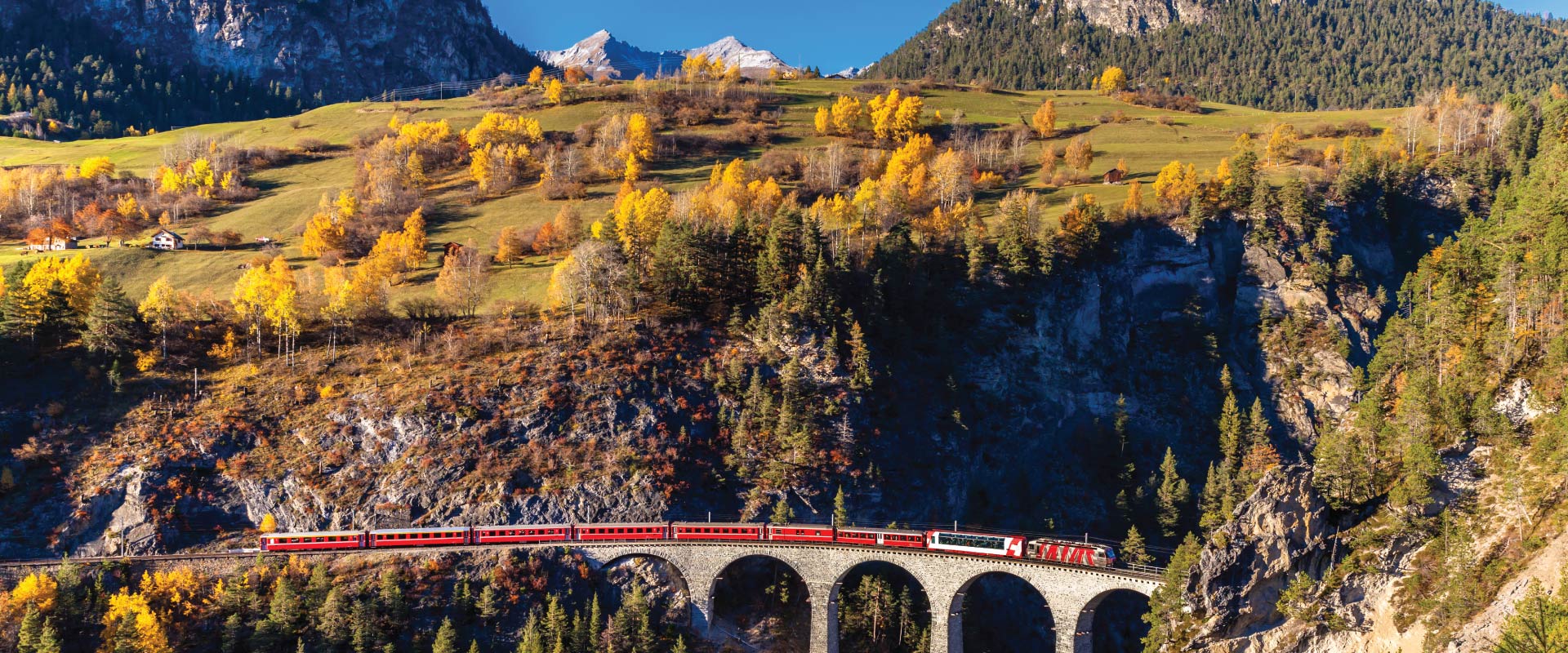Train travelling across via duct with huge mountains in the background, Switzerland