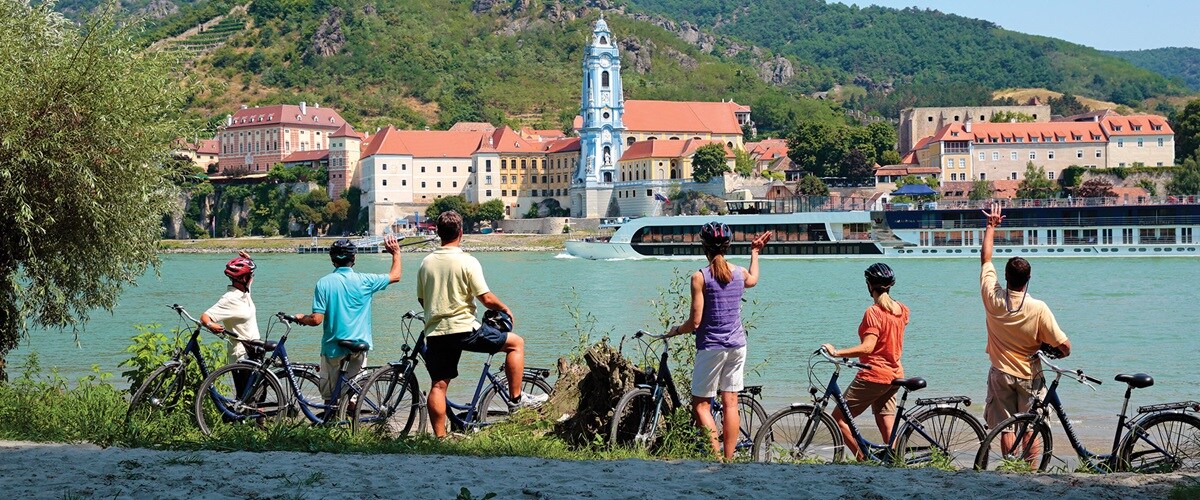 Passengers cycling along river, stopped to watch and wave at the ms Amariena sailing past, Durnstein, Austria