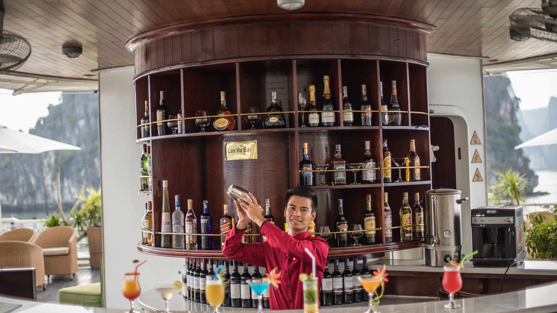 Bartender creating multiple colourful cocktails onboard the Au Co Ship, Ha Long bay, Vietnam