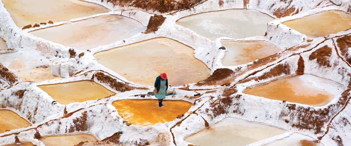 View of Orange lakes with a lone person standing in salt pool, Peru