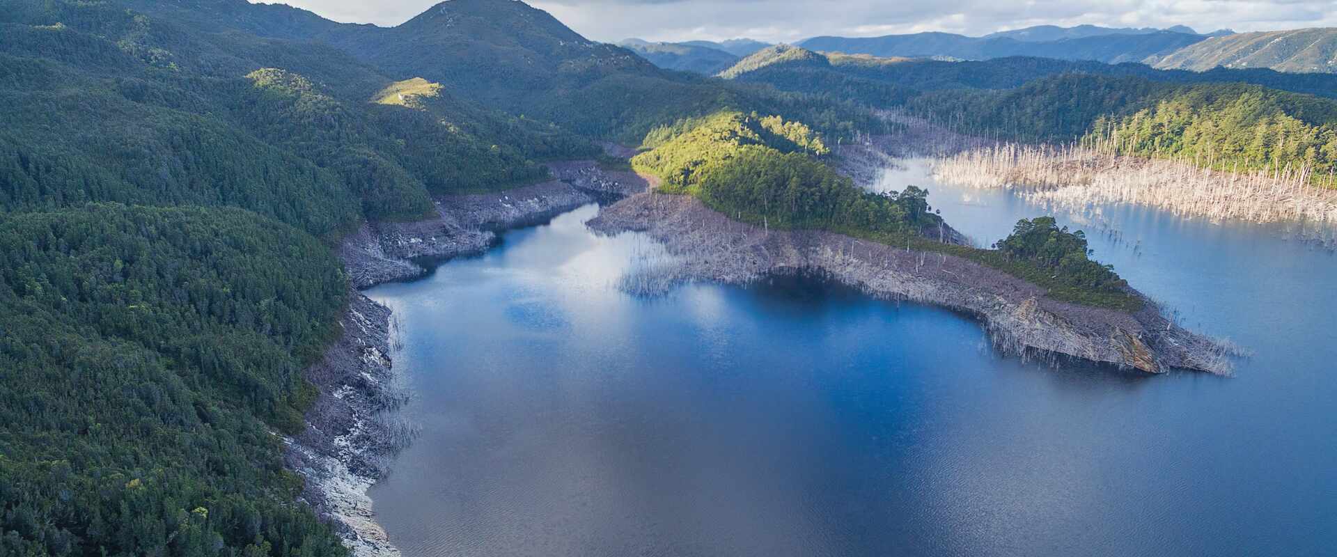 Aerial view of the rolling hills surrounding the dark waters of the Gordon River region, Tasmania